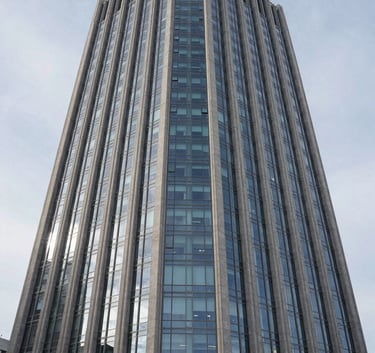 A sophisticated architectural photograph of a modern North American / US headquarters building reflecting a pale ice sky. The composition is sharp and symmetrical, emphasizing precision and stability.