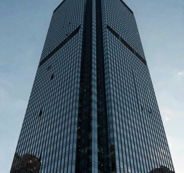 A low angle shot of a modern glass skyscraper in São Paulo, South American / Brazilian urban architecture, reflecting a clear sky, medium blue and dark charcoal blue tones, professional and trustworthy feel.
