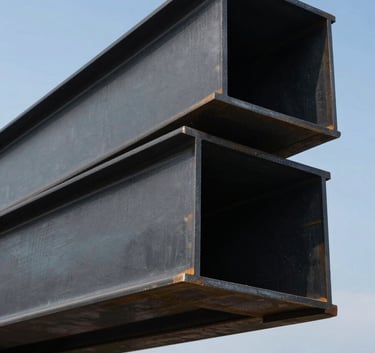 Dramatic low-angle shot of structural steel H-beams for an industrial project, charcoal black finish, precision engineering aesthetic, clear blue sky background, North American / Mexican construction site.