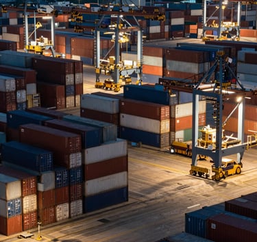 High-angle view of a bustling international cargo port at night, bright industrial lights reflecting off stacked multi-colored shipping containers, efficient and organized logistics operations.