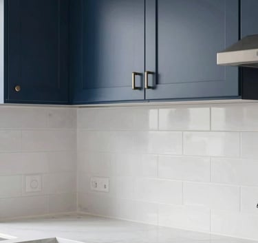 A close-up shot of a modern, minimalist kitchen with navy blue cabinetry and stunning white backsplash tile work in a North American / US residence.