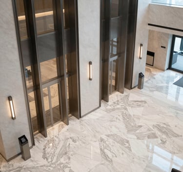 A high-angle view of a professional, modern corporate lobby with clean lines, marble floors, and glass elevators, North American / International Business setting, soft natural lighting.