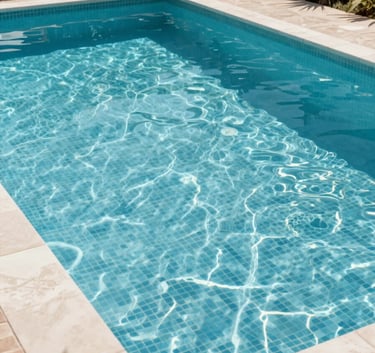 A wide-angle shot of a newly constructed swimming pool with crystal clear water and light blue mosaic tiles, set in a contemporary Mediterranean garden in Spain.