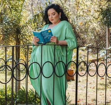 Raabe lendo livro em pé em um jardim.