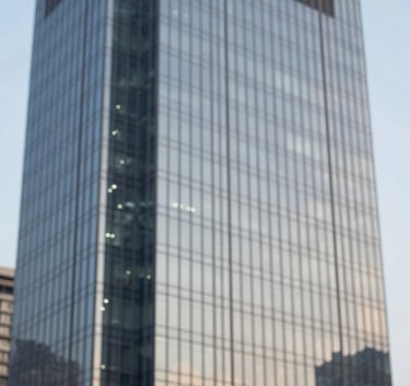 A sophisticated close-up of a modern skyscraper's glass exterior reflecting a clear sky, symbolizing growth and high-end commercial property in Haryana. Style is clean and minimalist with professional architectural photography lighting, using subtle blue tones.
