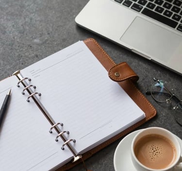 A top-down view of a professional desk in a modern Indian corporate setting, featuring a leather-bound planner, a sleek laptop, and a cup of masala chai.