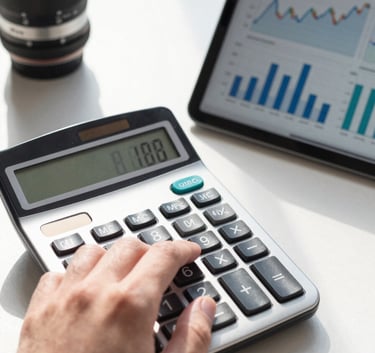 A close-up, sharp-focus shot of a hand using a professional calculator next to a tablet displaying financial growth charts. The setting is a bright, sunlit modern office in the US.