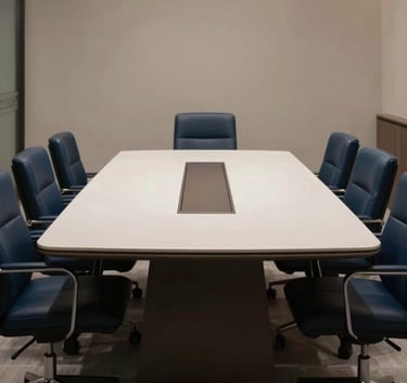 A high-end, minimalist boardroom table in a Lahore office suite with deep navy blue leather chairs and a soft off-white surface under professional lighting.