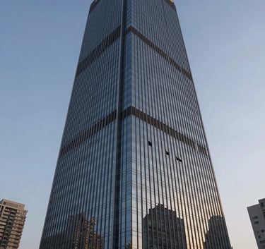 A low-angle shot of a stunning modern commercial skyscraper in Noida, featuring glass and steel, during the blue hour. The lighting is sophisticated and professional, reflecting a South Asian city atmosphere.