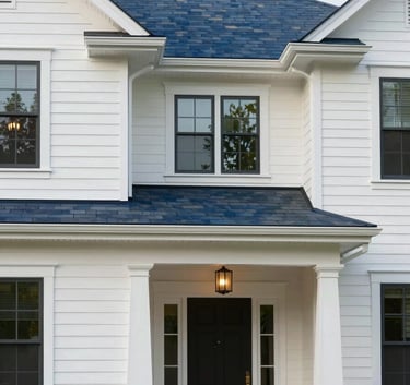 A luxury residential property in the Raleigh-Durham area. The house features soft off-white siding and dark slate blue architectural accents. Bright, professional photography.