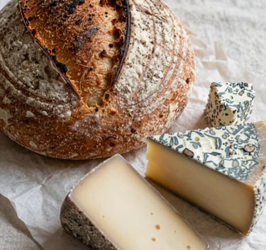 A Scandinavian-style close-up of artisanal sourdough bread and local cheeses on a crisp parchment linen cloth. North American farm-to-table aesthetic. Soft morning light, rustic textures, and professional food photography style.