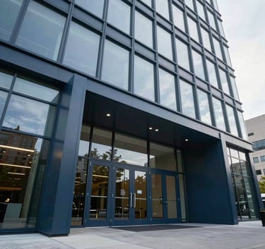 A low-angle exterior shot of a modern North American corporate headquarters featuring massive architectural glass and dark blue steel doors at the entrance.