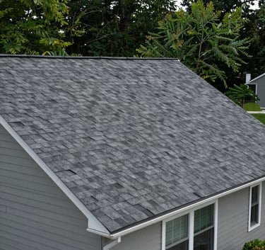 A clean residential home in New Jersey with a newly installed dark gray shingle roof, surrounded by green trees, professional photography style.