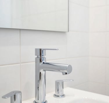 A high-end, modern bathroom in a Northern European / German / Hamburg residence featuring minimalist chrome fixtures and pristine white tiling. The photography focuses on the quality of the installation and clean lines. Bright, airy atmosphere with steel blue accents.