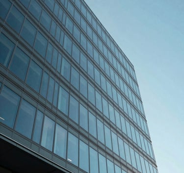 A low-angle exterior shot of a modern glass office building in Spokane, Washington, reflecting a clear blue sky. The architecture is sleek and professional, conveying financial stability and innovation. The lighting is bright and natural, typical of a crisp North American afternoon.