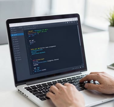 A clean, bright office setting showing a professional using a laptop with code on the screen, reflecting modern software development (C# .NET) and SAP Service Layer integration, styled with #F8F9FA and #2B6777 accents.