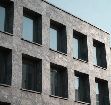 A minimalist building facade with repeating geometric windows and cool slate grey shadows, shot from a low angle under a clear, professional lighting setup.