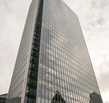 A sophisticated, low-angle shot of a glass skyscraper in London reflecting a soft off-white sky, captured with a clean and professional architectural photography style.
