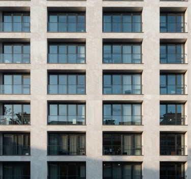 A crisp, architectural photograph of a high-end apartment complex facade in the United Kingdom, using muted blue and off-white tones, late afternoon lighting.