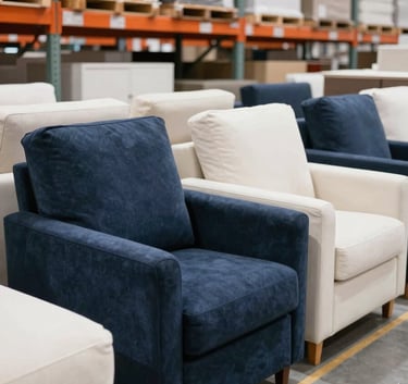 A high-end, bright photography of a professional wholesale warehouse in a Western European / Dutch industrial area. The space is filled with neatly stacked, modern household furniture. The lighting is crisp, highlighting deep navy blue and off-white tones.