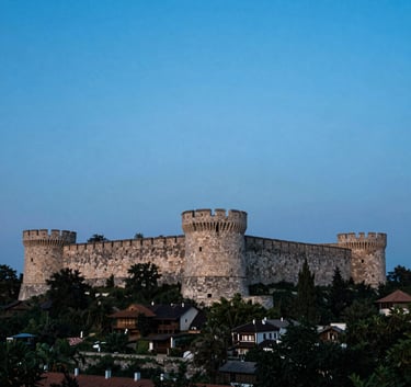 A wide-angle professional photograph of the Belgrade Kalemegdan fortress at dusk, soft light blue and steel blue sky, Eastern European / Balkan, with South Asian / Southeast Asian focus, cinematic composition.