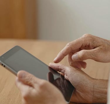Close-up of a senior person's hands comfortably using a tablet, guided by a young professional's hand, warm and approachable vibe with orange accents.