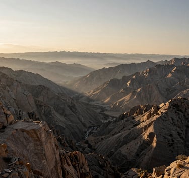 Wide-angle landscape of the North American Rocky Mountains at dawn, misty valleys, muted tan peaks, professional outdoor photography style. No people.