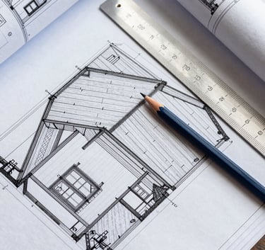 A top-down professional shot of detailed architectural blueprints for a roofing project, with a silver ruler and a dark blue pencil, modern and efficient atmosphere, European / French style.