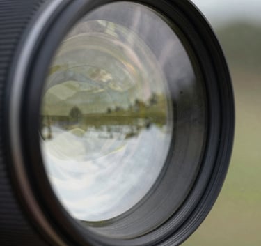 A detailed photograph of high-quality, OEM-standard glass showing a slight reflection of a clean North American landscape. The image uses a soft focus on the background with sharp, clear focus on the glass surface, conveying integrity and quality.