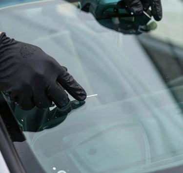 Close-up of a high-quality, clear automotive windshield glass being installed by gloved hands. Focus on the precision and the clean, light blue reflections on the glass. North American setting.