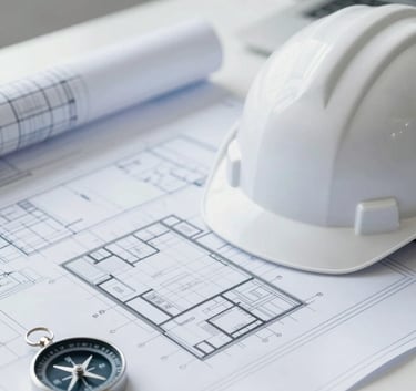 A clean, corporate desk view featuring professional blueprints, a white hard hat with a subtle blue logo, and a compass. Soft natural lighting, minimal style. The color palette emphasizes #F5F8FA and #7D9DB2 to convey trust and engineering precision.
