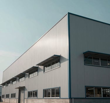 A low-angle shot of a newly constructed modern industrial warehouse with sharp lines, against a Soft Mist Blue sky, emphasizing reliability and scale.