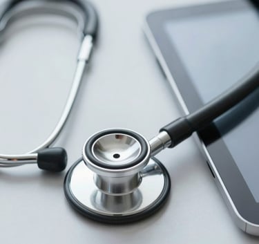 A close-up, high-key image of a modern stethoscope resting on a clean, light gray surface next to a digital tablet. The lighting is soft and professional, incorporating a palette of #B4D4DF and #1A2F3D.