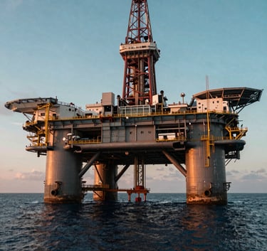 Wide shot of a massive offshore oil rig at sunset, emphasizing complex engineering and energy sector scale, cinematic lighting with teal and dark blue ocean water.