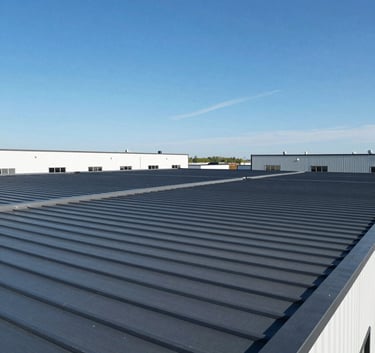 A wide shot of a modern industrial commercial building with a newly installed dark gray flat roofing system in North American / US - New Jersey. Clear blue sky, sharp lighting, and clean lines reflecting professional construction.
