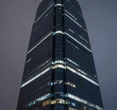 A high-tech glass skyscraper at night, illuminated with subtle mist grey and deep midnight blue lights, reflecting a sense of corporate power and innovation.