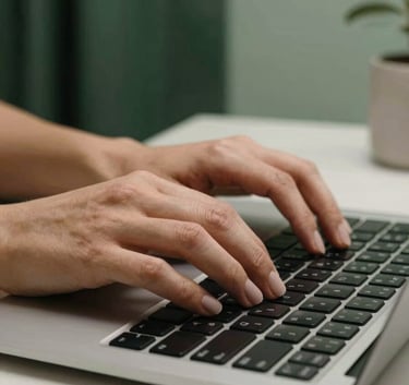 A sharp, professional photograph of a person's hands typing on a sleek keyboard. The environment is clean and modern, featuring forest green and muted sage decorative elements in the background.