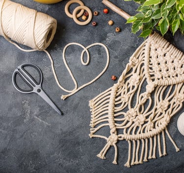 Tapiz de macramé hecho a mano con cordón de algodón, aros de madera y tijeras.