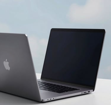 A close-up of a high-tech sleek laptop on a minimalist white desk in a room with soft pale cloud blue lighting.
