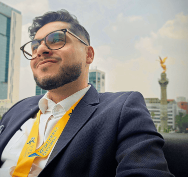 Professional man in a suit with the Angel of Independence monument in Mexico City behind him.