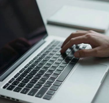 A close-up shot of a professional's hands typing on a high-end laptop in a sleek British / UK workspace, focus on technical precision, lighting in pale blue-grey tones.