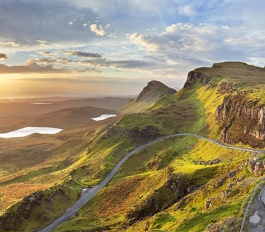 a winding road in the mountains with a sunset