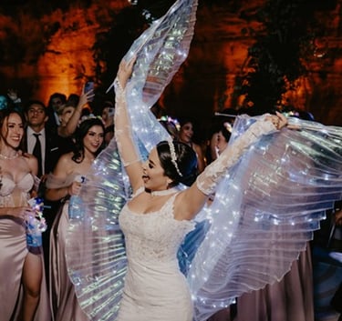 Novia muy contenta bailando con velo iluminado por luces led el día de boda, atrás de ella sus damas