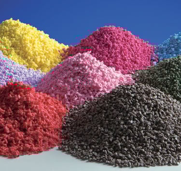Mounds of colorful recycled plastic granules and polymer pellets for industrial manufacturing.