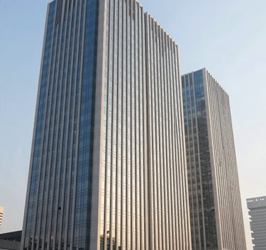 A wide-angle shot of a modern corporate glass building in a South Asian financial district under a clear morning sky. The composition is clean and architectural, highlighting professional trust and sophisticated engineering with off-white and deep blue tones.