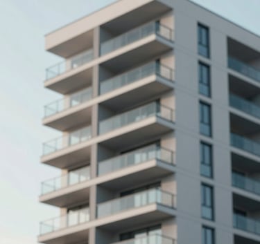 A modern apartment building facade with clean lines and glass balconies under a clear sky, edited with a professional, slightly desaturated look using the palette tones #4C6A7F and #F8F8F4.