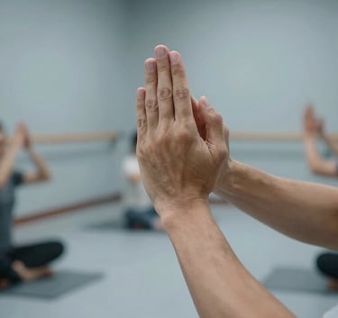 A serene North American indoor training space with clean lines and light blue-grey walls. The composition shows a close-up of hands performing a meditative Qi Gong gesture, reflecting precision and calm professionalism.