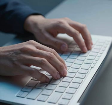 A high-quality photo of hands typing on a sleek keyboard, focus on the fingers, in a professional Central European / German digital studio, utilizing Pale Silver Blue and Muted Steel Blue lighting.