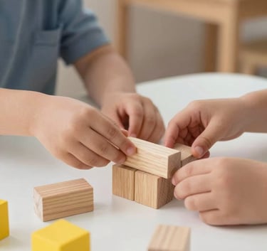 Close-up photography of a child's small hands playing with wooden blocks and yellow building toys on a white table. Professional, soft focus, bright natural lighting, North American / US preschool setting.