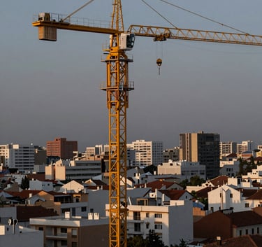 A high-angle professional photograph of a large yellow construction crane operating in the Cordoba cityscape at dusk. The sky has muted blue grey tones, and the machine reflects soft professional off-white light.
